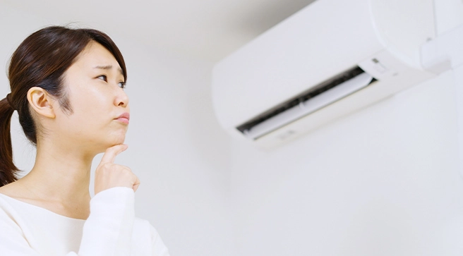 エアコンを眺めながら困った様子の女性